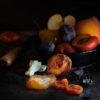 Dried fruit and a apricot peach plum apple and pear in a bowl